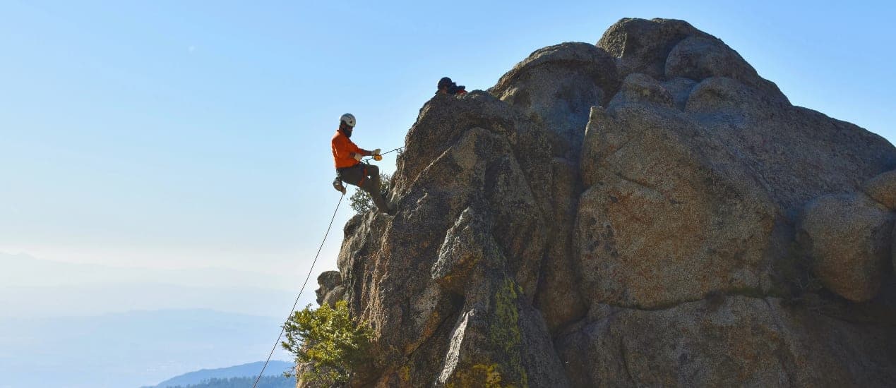 An SDMRT rescuer rappelling a granite face